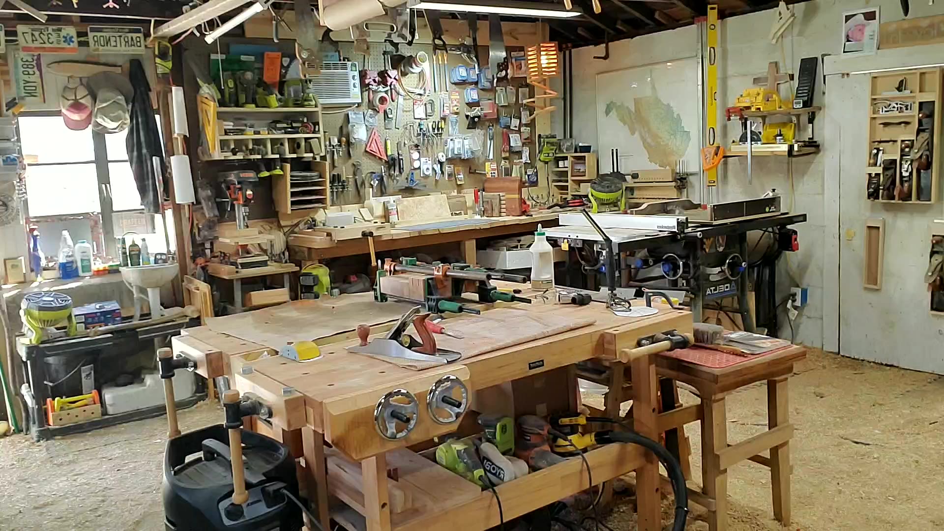 Ben Kiger's woodworking shop in Williamstown, West Virginia — workbench, hand tools, and a West Virginia state map on the wall